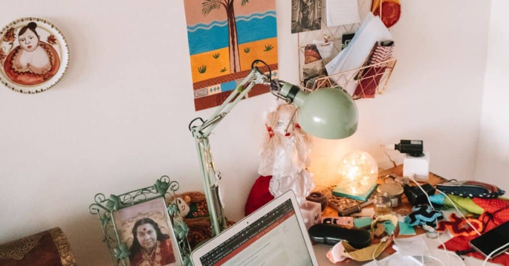 A well-used desk setup with a laptop, lamp, and personal touches, ideal for remote work inspiration.